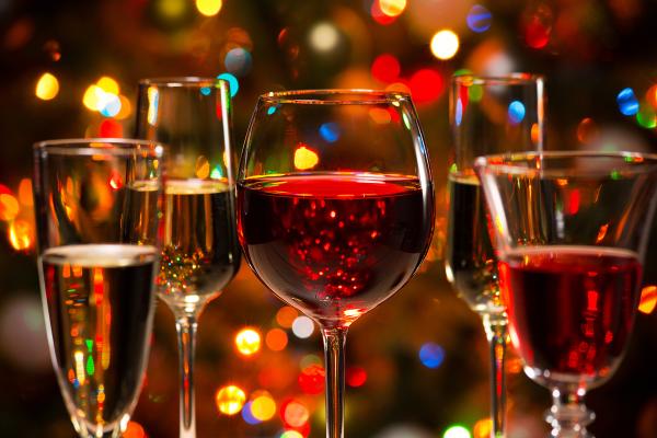 Multiple wine glasses with various kinds of red and white wine, featured in front of Christmas lights
