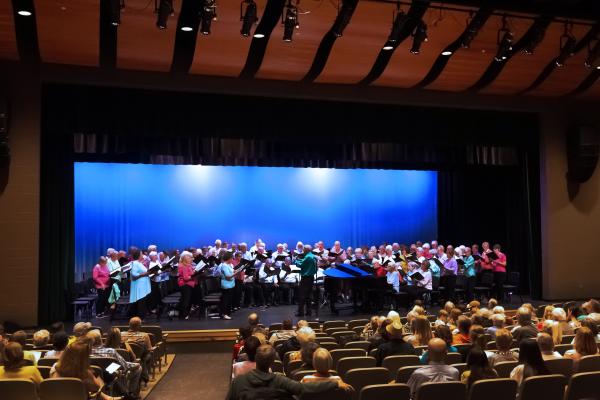 A wide shot of the OLLI Chorus Ensemble along with the members of the crowd shown inside of Frederick Douglass High School Auditorium during the Spring 2025 concert.